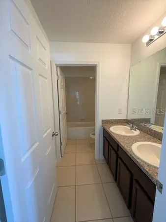 a bathroom with a granite countertop sink a toilet and a mirror