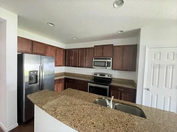 a kitchen with stainless steel appliances granite countertop a sink stove and refrigerator