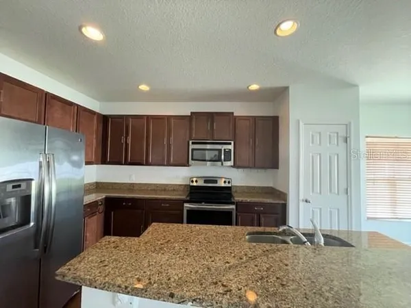 a kitchen with kitchen island granite countertop a stove sink and refrigerator