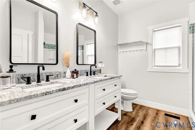 a bathroom with a granite countertop toilet sink and mirror