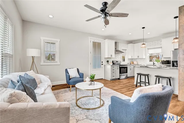 a living room with furniture kitchen view and a chandelier