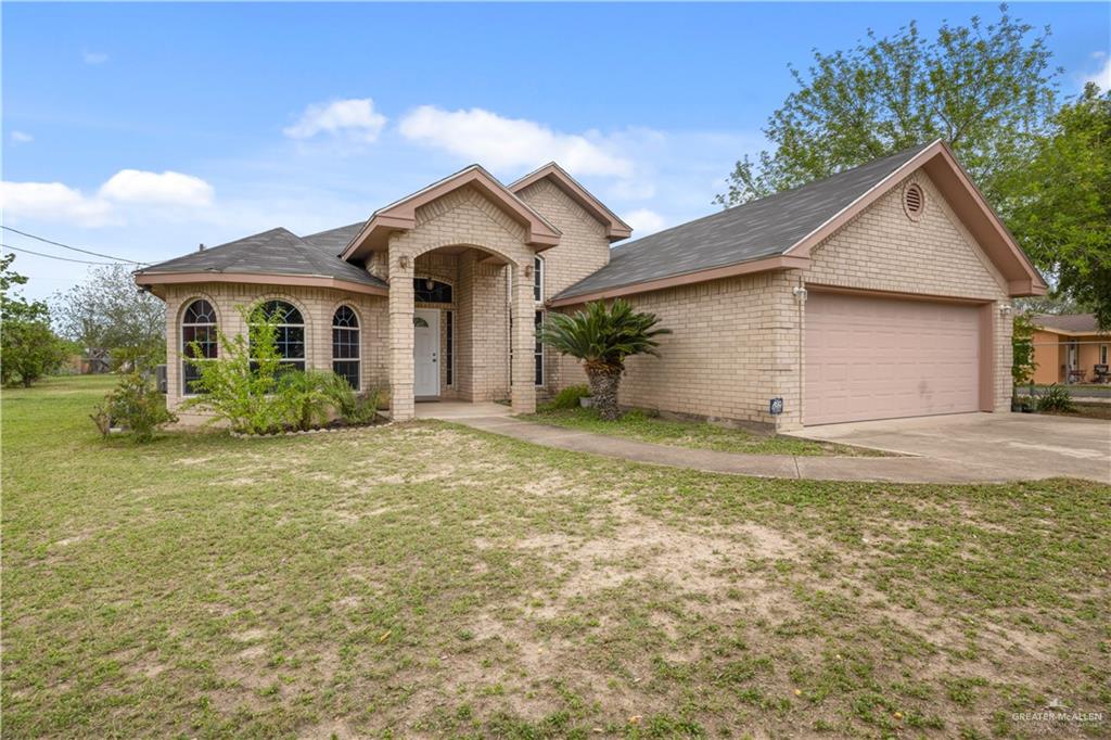 6020 North Doolittle Road Edinburg, TX 78542 - Photo 2 of 23 Light brick exterior with an arched entry, a two-car garage, multiple arched windows, and a manicured lawn