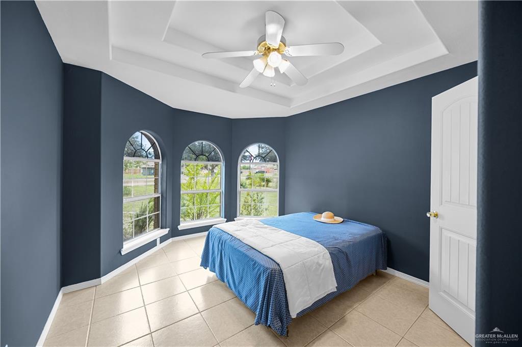 6020 North Doolittle Road Edinburg, TX 78542 - Photo 9 of 23 Room featuring three arched windows, a tray ceiling with a ceiling fan, and tile flooring