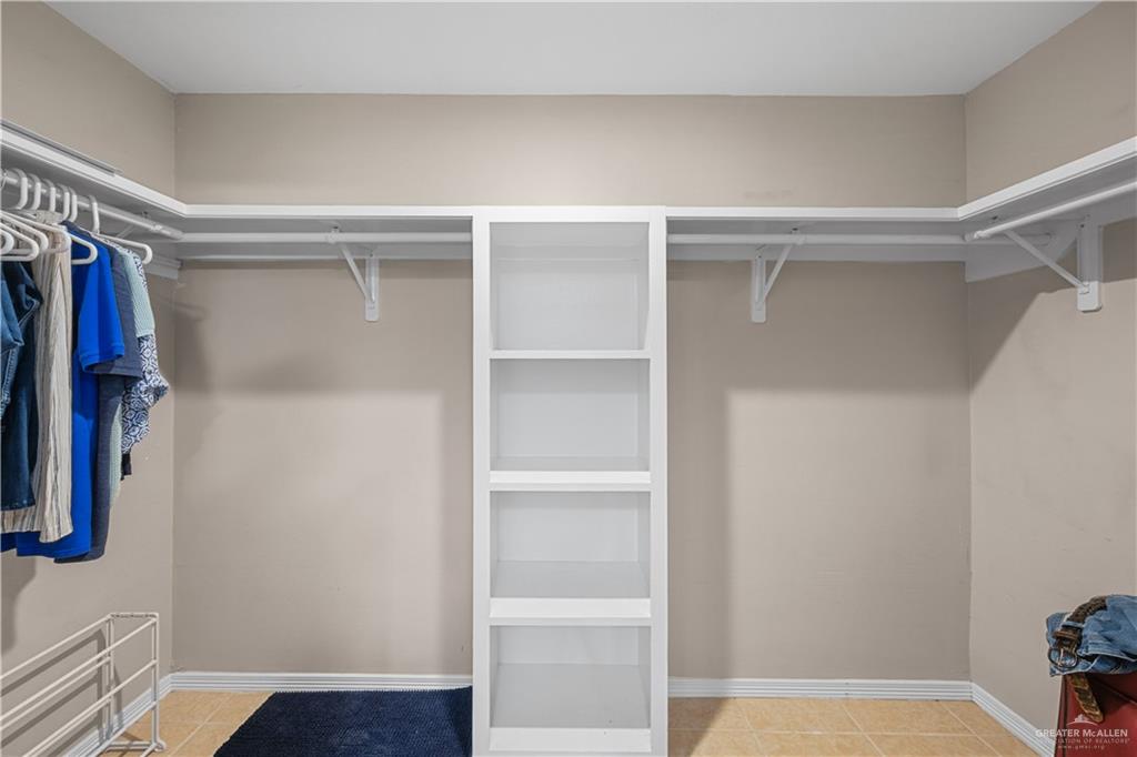 6020 North Doolittle Road Edinburg, TX 78542 - Photo 10 of 23 Walk-in closet featuring built-in shelving, multiple hanging rods, and neutral-toned walls