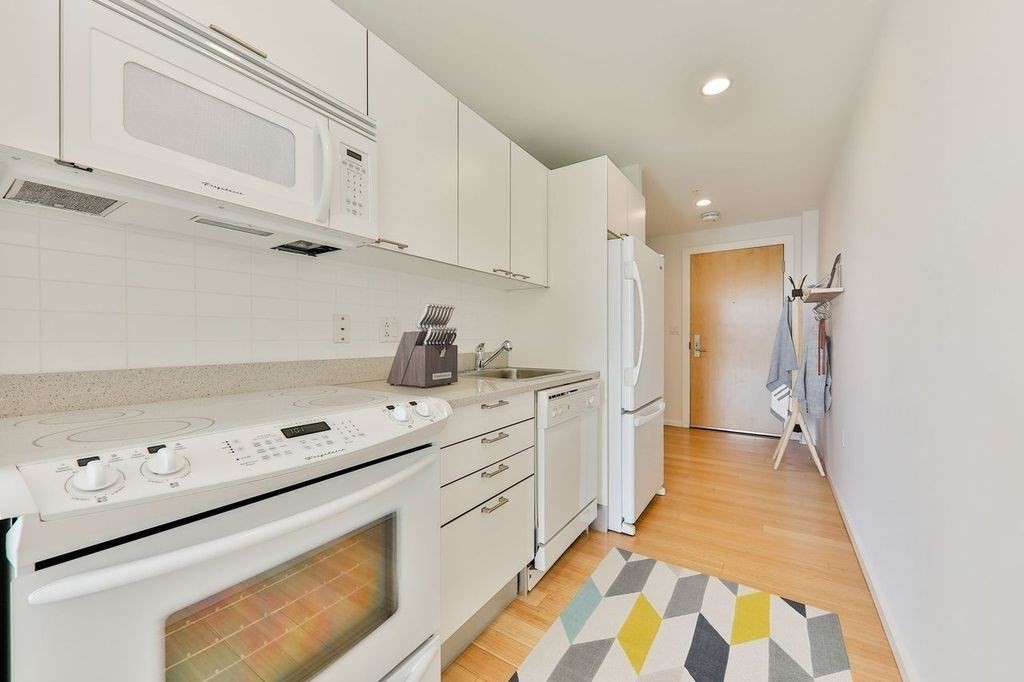 2 Earhart Street, Unit 720 Cambridge, MA 02141 - Photo 7 of 40 a kitchen with white cabinets and white appliances