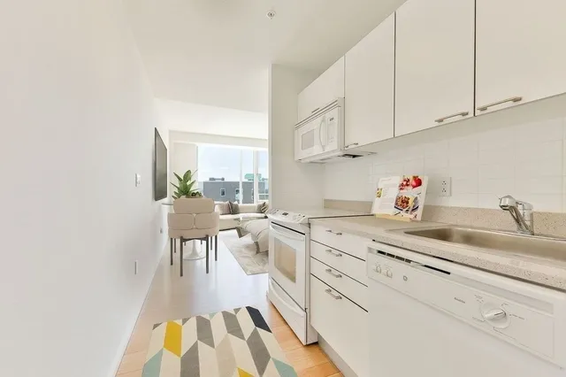 a kitchen with white cabinets and sink