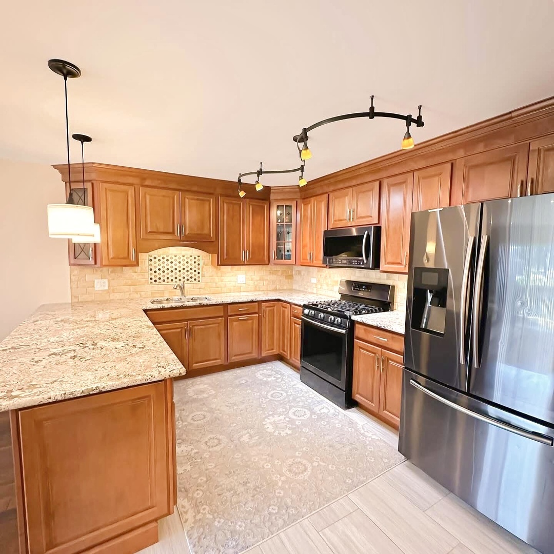 1575 Sandpebble Drive, Unit 104 Wheeling, IL 60090 - Photo 2 of 8 a kitchen with stainless steel appliances granite countertop a refrigerator a stove and a sink with wooden floors