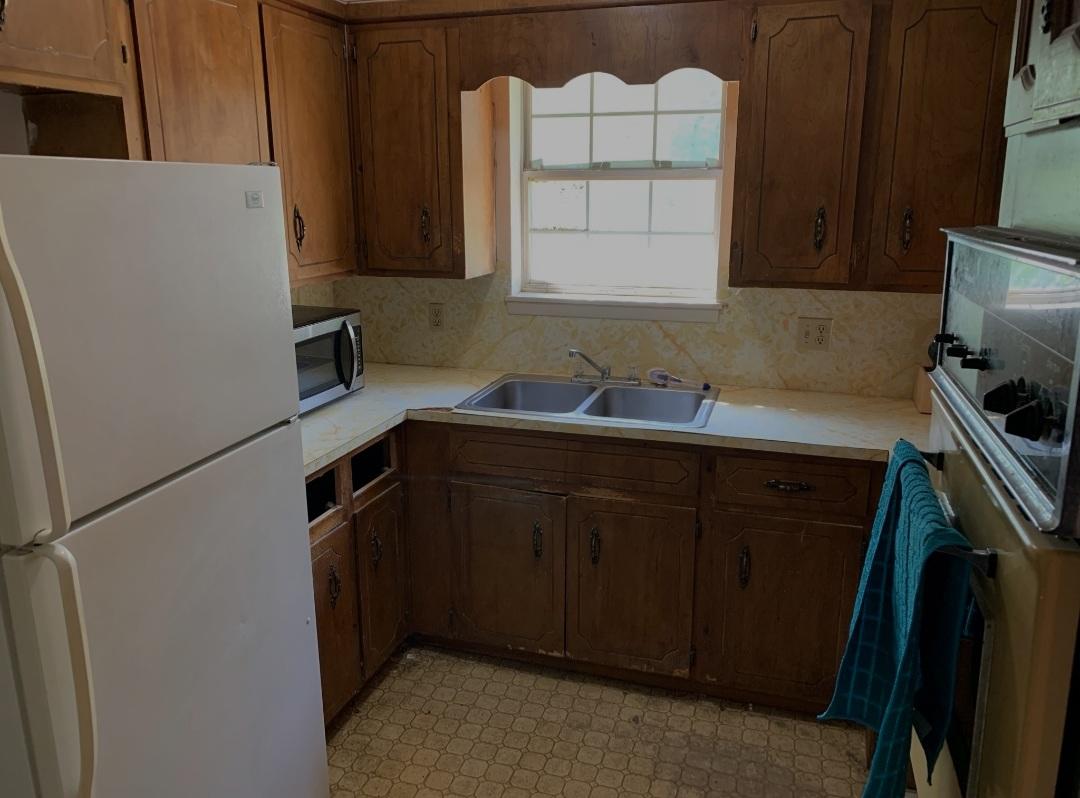1470 Reddick Mill Road Graceville, FL 32440 - Photo 5 of 11 a kitchen with a sink a refrigerator and cabinets