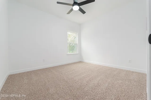 an empty room with a window and a fan