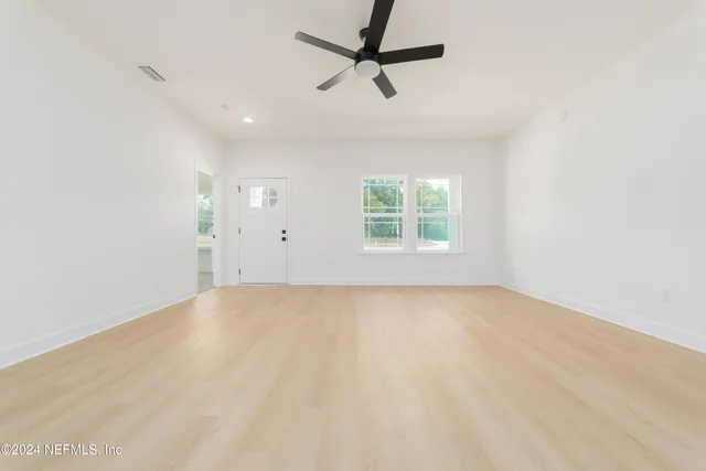 an empty room with windows and fan