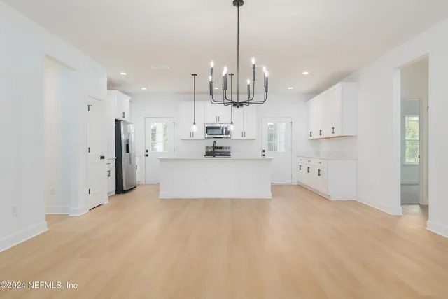 a view of a kitchen with refrigerator and white cabinets