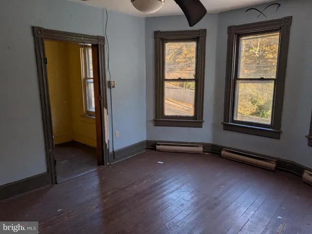 an empty room with wooden floor and windows