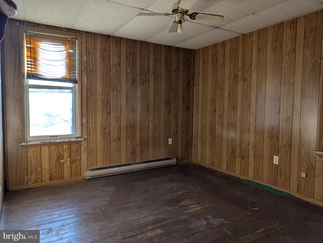 an empty room with wooden floor closet fan and windows