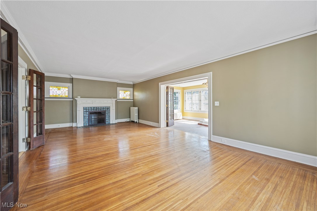 24510 Lake Road Bay Village, OH 44140 - Photo 13 of 45 Unfurnished living room featuring light wood-type flooring, healthy amount of natural light, a tile fireplace, ornamental molding, and radiator