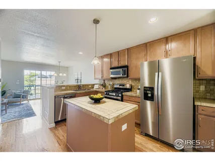 a kitchen that has a refrigerator a stove a sink dishwasher a oven with white cabinets and wooden floor