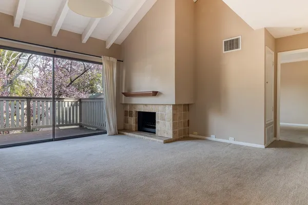 an empty room with floor to ceiling windows and fireplace