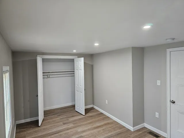 a view of an empty room with wooden floor & closet area