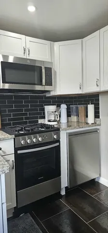 a kitchen with granite countertop a stove and a microwave