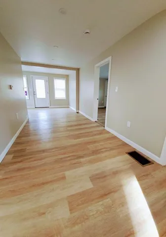 a view of an empty room with wooden floor and window