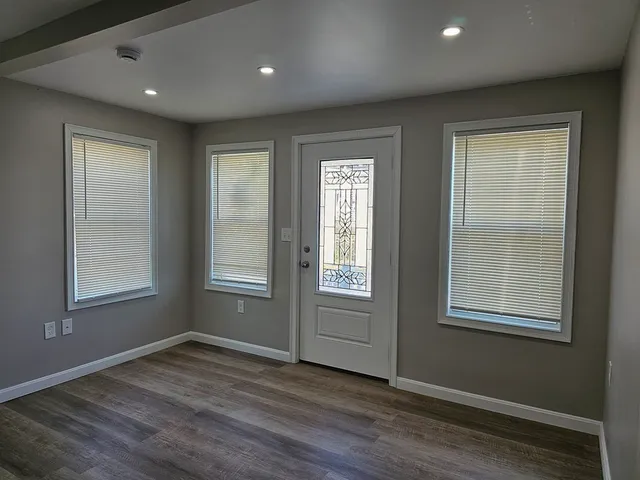 an empty room with wooden floor and windows
