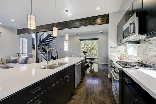 a kitchen with stainless steel appliances a sink stove and wooden floor