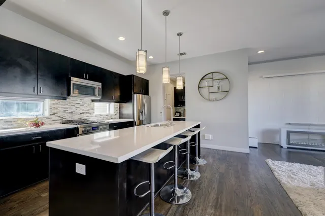 a kitchen with a table chairs a sink dishwasher stove and cabinets with wooden floor