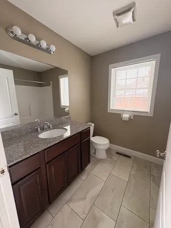a bathroom with a granite countertop sink toilet and mirror