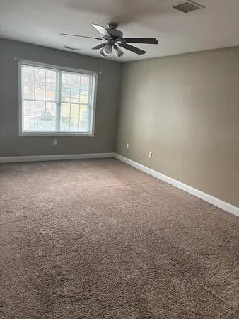 an empty room with windows and chandelier fan