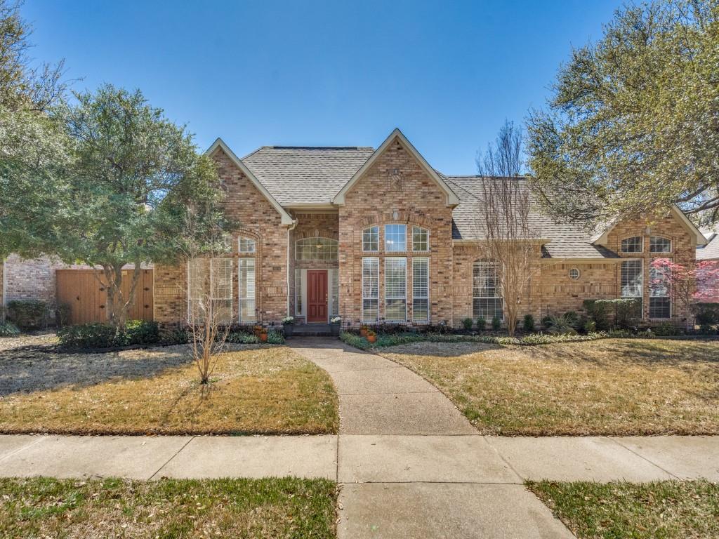 Traditional-style home featuring a front yard, brick siding, and roof with shingles