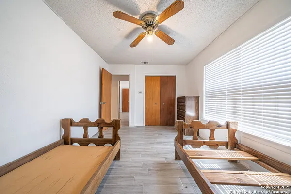 a view of empty room with wooden floor and fan