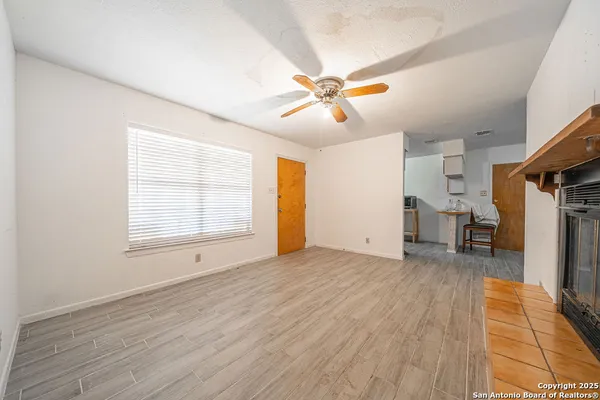 a view of an empty room with window a ceiling fan and wooden floor
