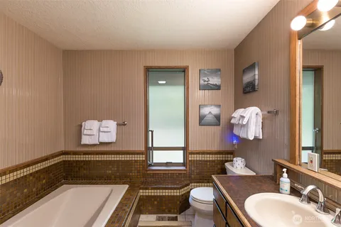 a bathroom with a tub sink and mirror
