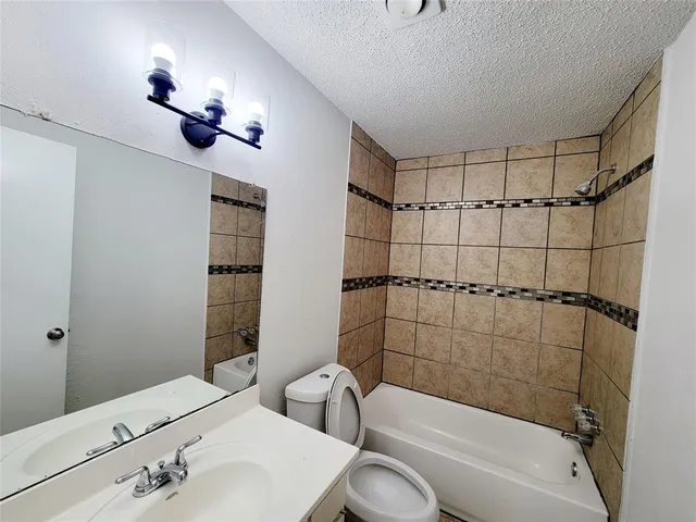 a bathroom with a bathtub shower sink vanity and toilet