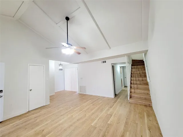 a view of a room with wooden floor ceiling fan and window