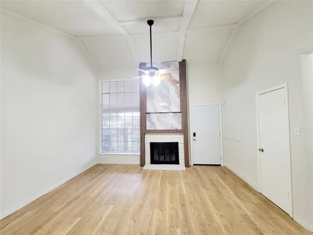 a view of an empty room with wooden floor fireplace and a window