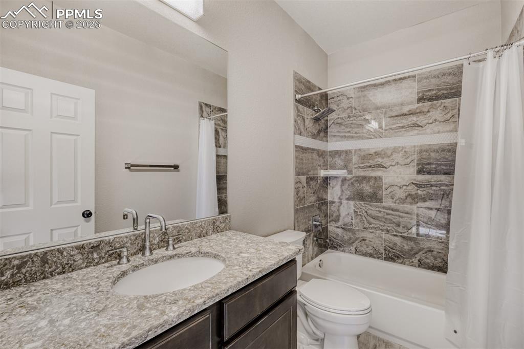 13680 Woodlake Road Elbert, CO 80106 - Photo 13 of 38 a bathroom with a granite countertop sink toilet a mirror a vanity and shower