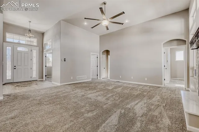 a view of a livingroom with a fireplace a ceiling fan and windows