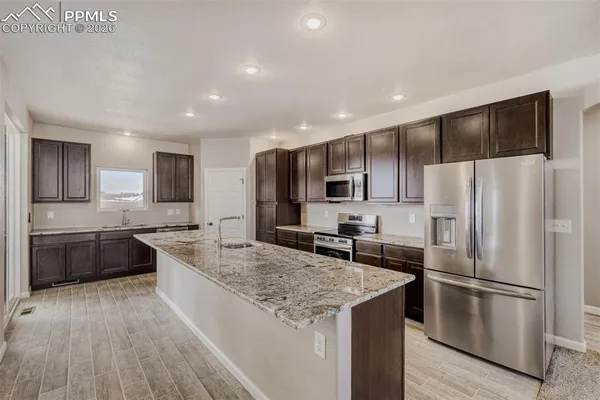 a kitchen with stainless steel appliances granite countertop a kitchen island a stove and a sink