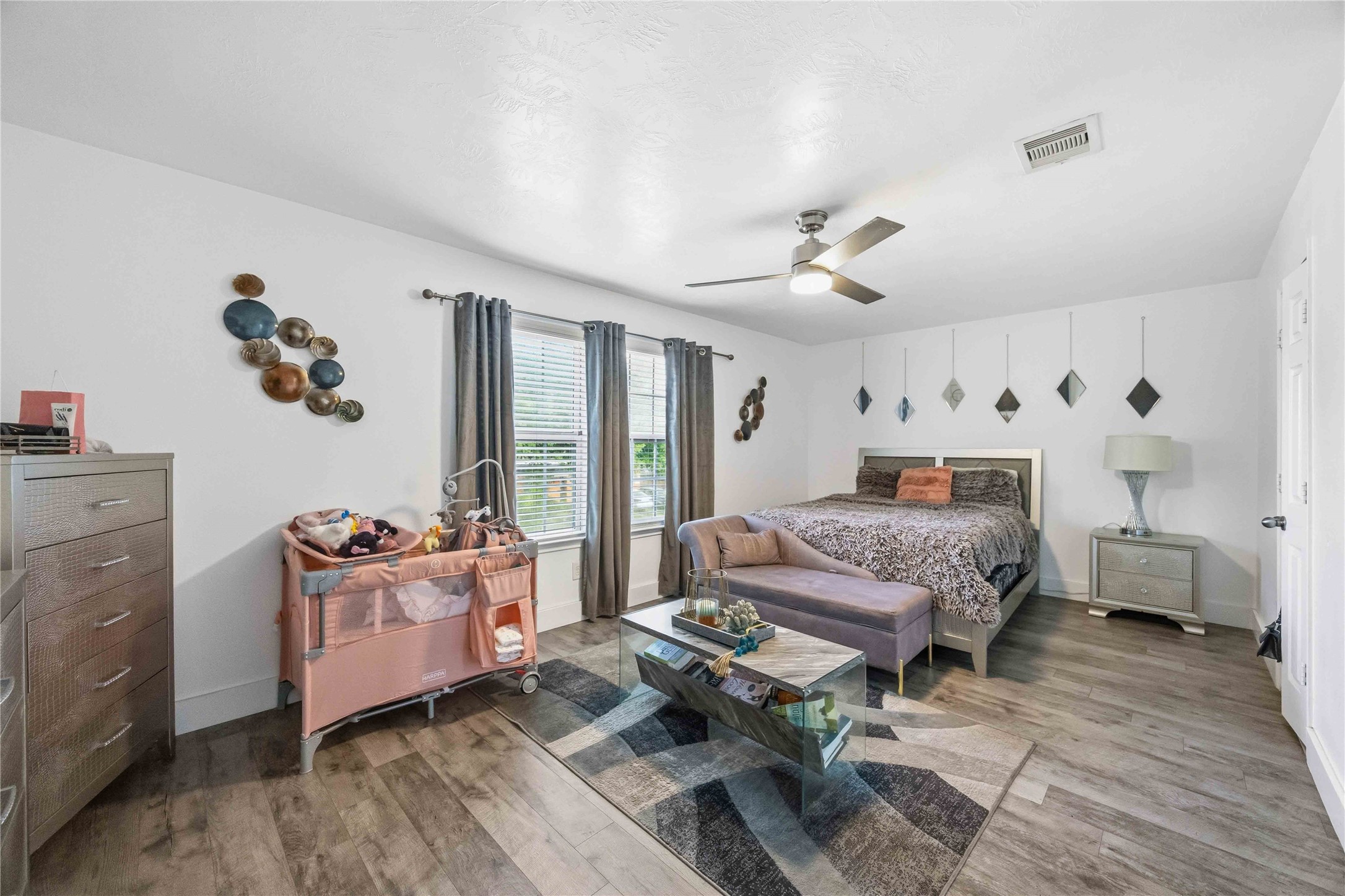 3538 Maris Way Humble, TX 77338 - Photo 12 of 24 Spacious and comfortable primary bedroom featuring durable wood-look flooring, neutral paint tones, and abundant natural light from multiple windows. A ceiling fan adds comfort, while the open layout easily accommodates a full bedroom set with additional seating or lounge space. A relaxing retreat with a clean, modern feel and flexible design options.