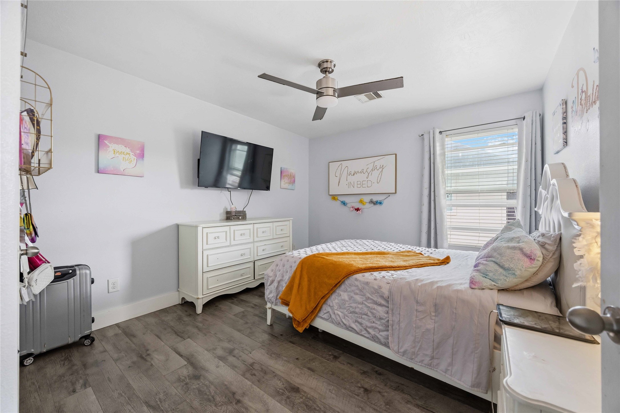 3538 Maris Way Humble, TX 77338 - Photo 16 of 24 Bright and comfortable bedroom featuring wood-look flooring, ceiling fan, and natural light from a large window. Spacious layout easily accommodates a full bedroom set with room to personalize.
