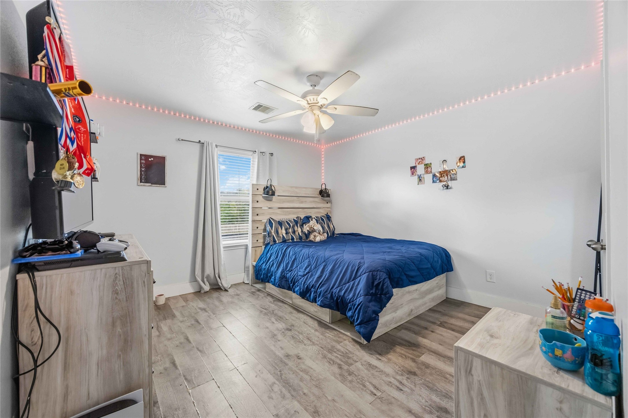 3538 Maris Way Humble, TX 77338 - Photo 18 of 24 Comfortable bedroom featuring wood-look flooring, ceiling fan, and soft neutral tones. Bright window provides natural light, with a spacious layout ideal for a bedroom set and personal storage.