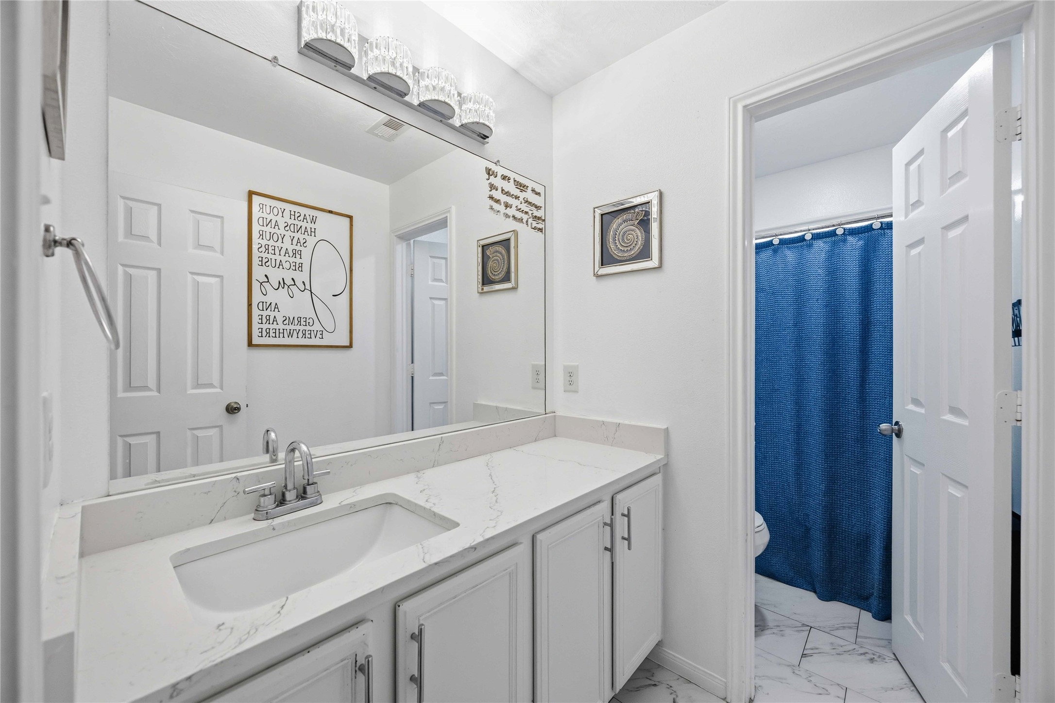 3538 Maris Way Humble, TX 77338 - Photo 19 of 24 Clean and modern bathroom featuring a spacious single-sink vanity, sleek countertop, and oversized mirror with contemporary lighting. Bright white finishes and functional layout provide a fresh, polished look with ample storage.