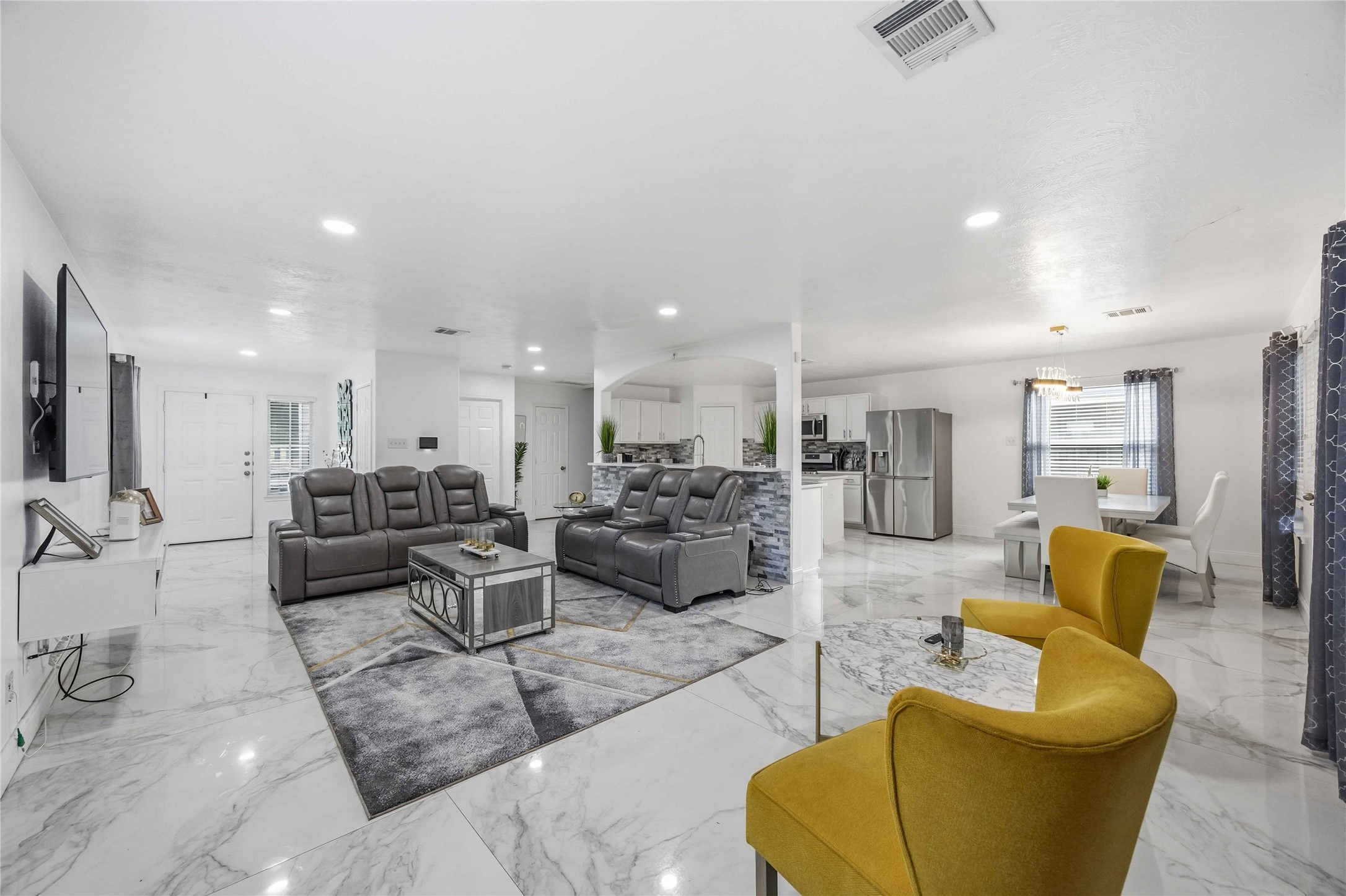 3538 Maris Way Humble, TX 77338 - Photo 5 of 24 Spacious open-concept living area featuring elegant marble-look tile flooring, recessed lighting, and a seamless flow between living, dining, and kitchen spaces. The generous seating area is anchored by a modern accent rug, with bright natural light enhancing the airy, contemporary feel. Ideal for both everyday living and entertaining, with clear sightlines and a functional layout throughout.