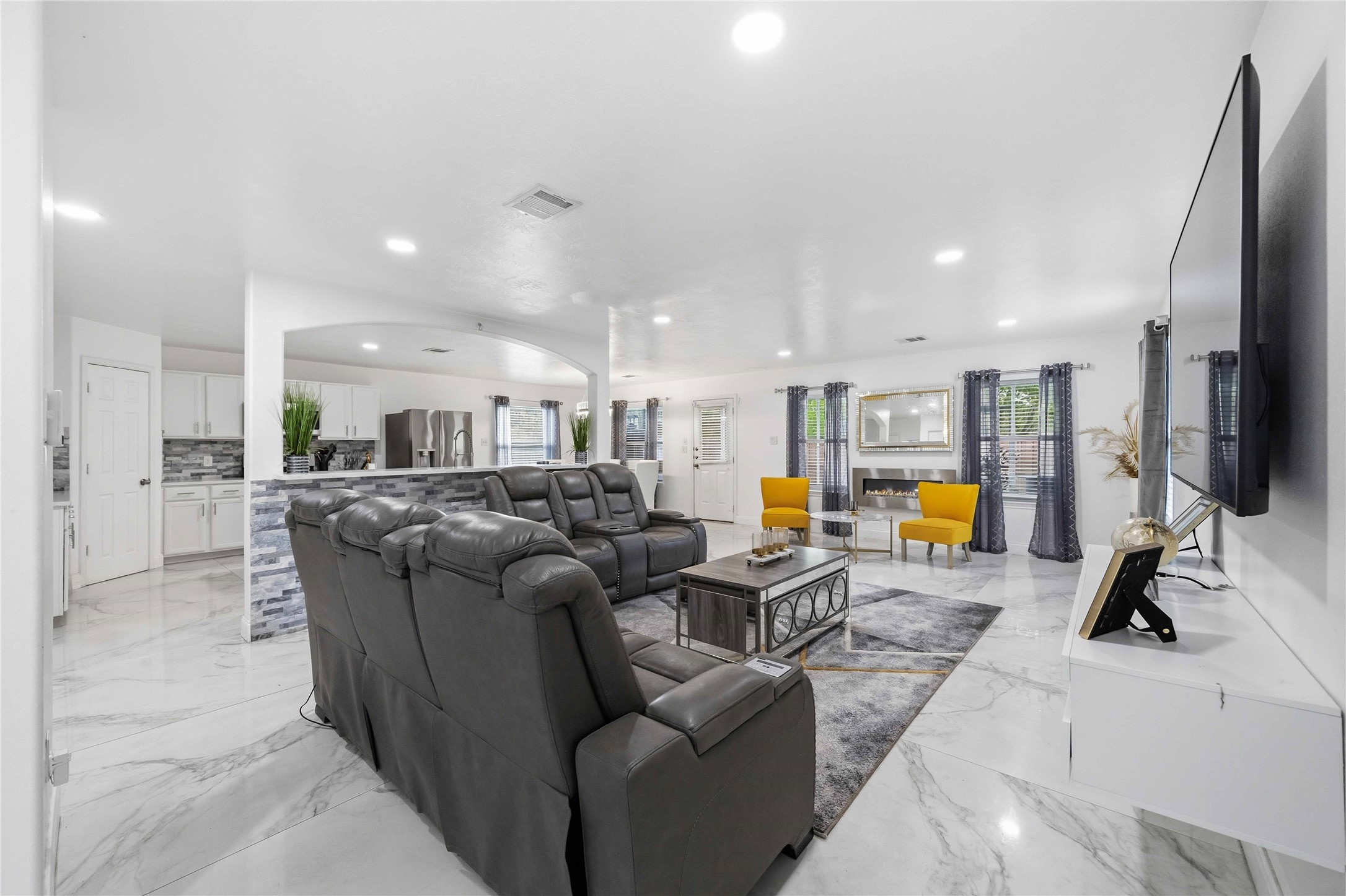 3538 Maris Way Humble, TX 77338 - Photo 7 of 24 Spacious open-concept living area featuring elegant marble-look tile flooring, recessed lighting, and seamless flow into the kitchen, creating a bright, modern space ideal for entertaining and everyday living.