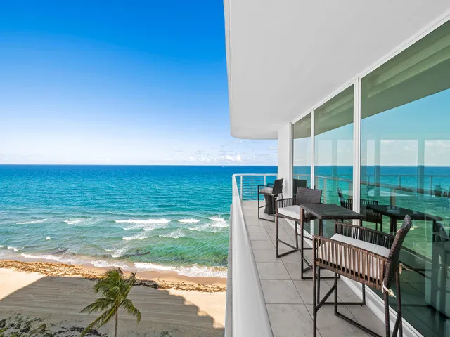a view of an ocean with a table and chairs in patio