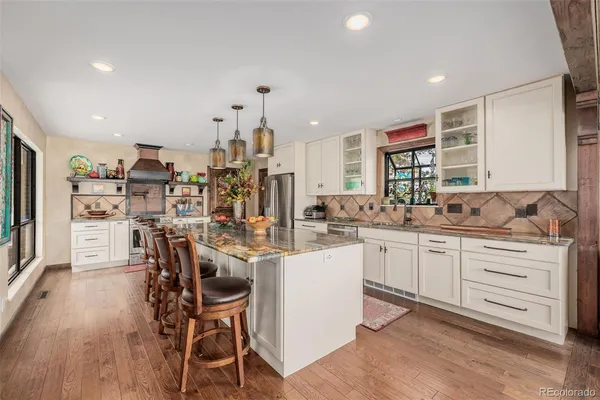 a kitchen with stainless steel appliances kitchen island granite countertop lots of wooden cabinets a dining table and chairs