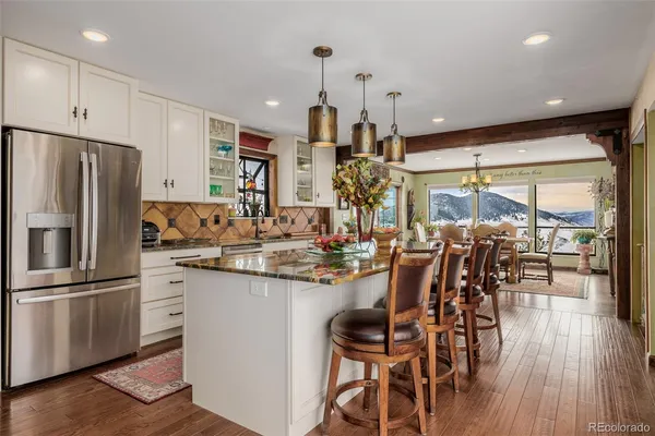 a kitchen with stainless steel appliances a dining table chairs and wooden floor