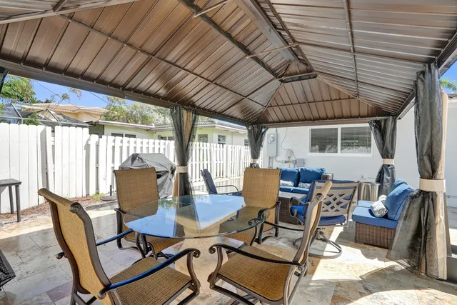 a view of a patio with table and chairs and couches with wooden floor and fence
