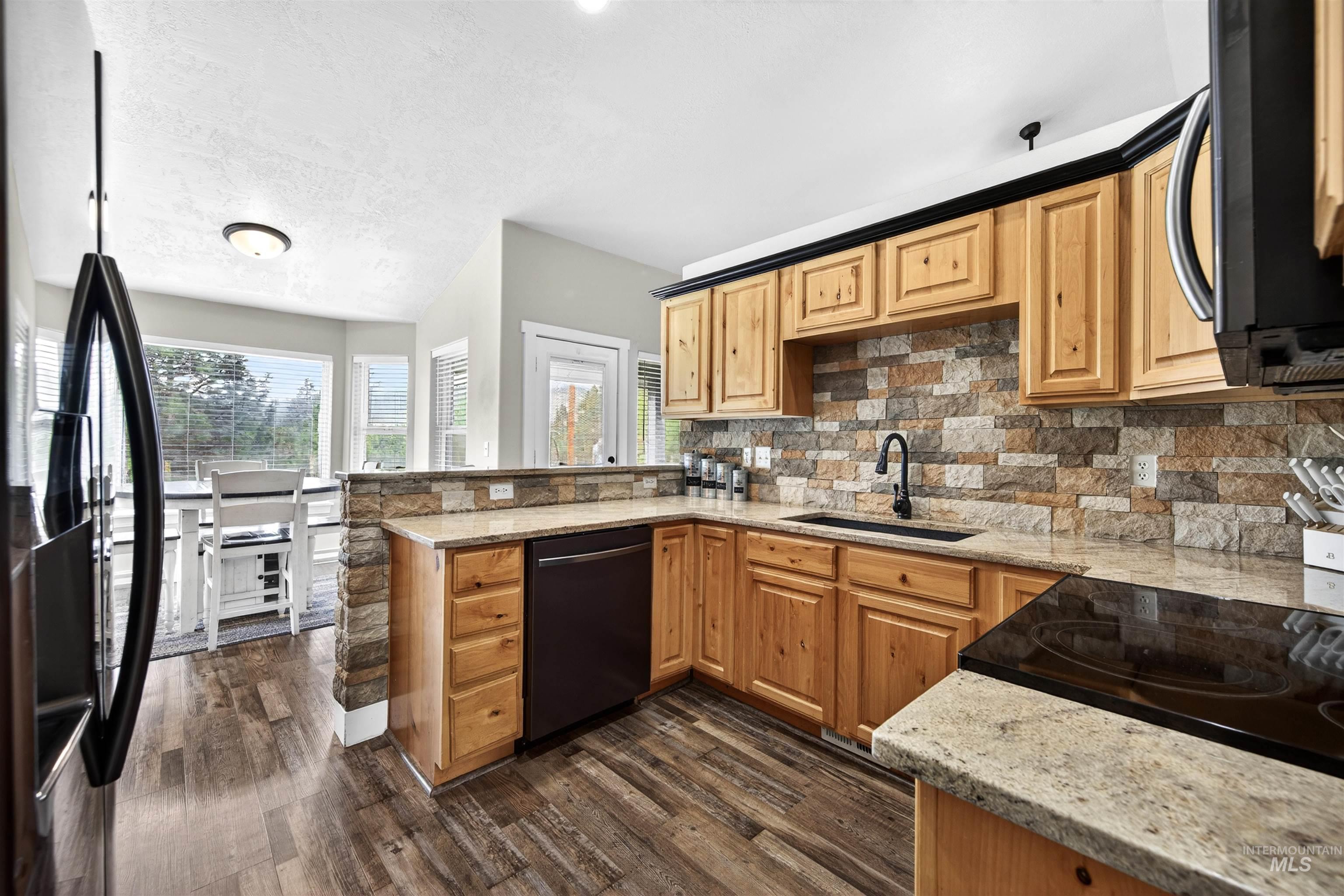 4 Round Up Circle Boise, ID 83716 - Photo 8 of 47 Kitchen featuring wood-finish flooring, light wood cabinetry, stone backsplash, light-toned countertops, and a built-in electric cooktop