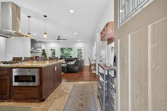 a kitchen with a stove a counter space and a view of living room